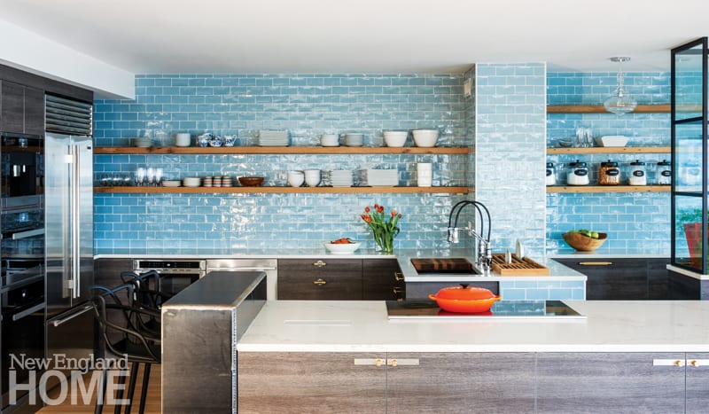 Large open kitchen with blue subway tile backsplash from the countertop to the ceiling. Open shelving featuring dishes. Stainless steel appliances.